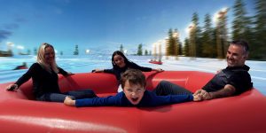 Family In Big Tube On Snowy Slopes