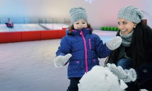 Mother & Daughter Building Snowman In Arctic Igloo