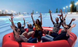 Group In Large Snow Tube Heading Down Slope
